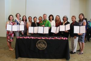 The Women's Legislative Caucus holds copies of their signed bills.