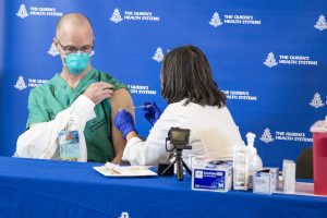 Dr. Lester Morehead, a hospitalist in The Queen’s Medical Center’s COVID-19 unit, received the first COVID-19 vaccination in the state from APRN Ruby Takahashi.