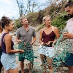 Kiai Collier of Hawaiʻi Land Trust and volunteers remove fishing nets from the beach.