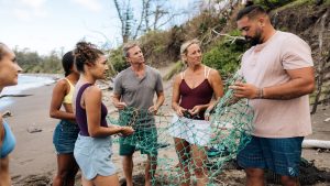 Kiai Collier of Hawaiʻi Land Trust and volunteers remove fishing nets from the beach. 